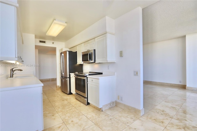 kitchen with baseboards, a sink, stainless steel appliances, light countertops, and white cabinetry