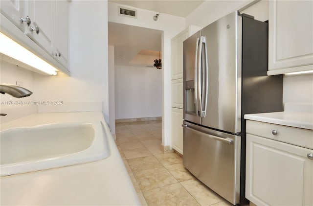 kitchen featuring visible vents, a sink, light countertops, white cabinets, and stainless steel refrigerator with ice dispenser