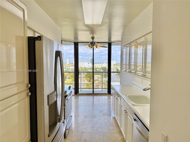 bathroom featuring ceiling fan, a wall of windows, light tile patterned floors, sink, and white cabinetry