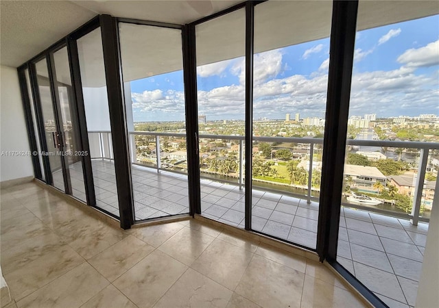 doorway to outside with light tile patterned floors, a view of city, and a wall of windows