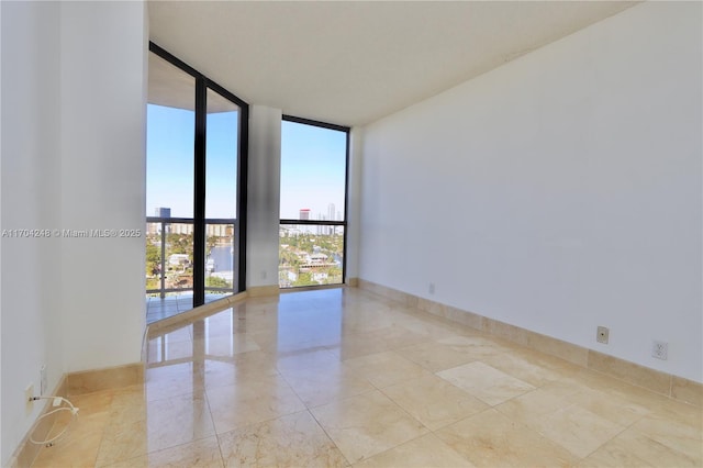 unfurnished room featuring a wall of windows and baseboards