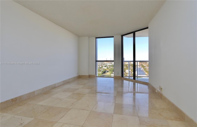 spare room featuring baseboards and expansive windows