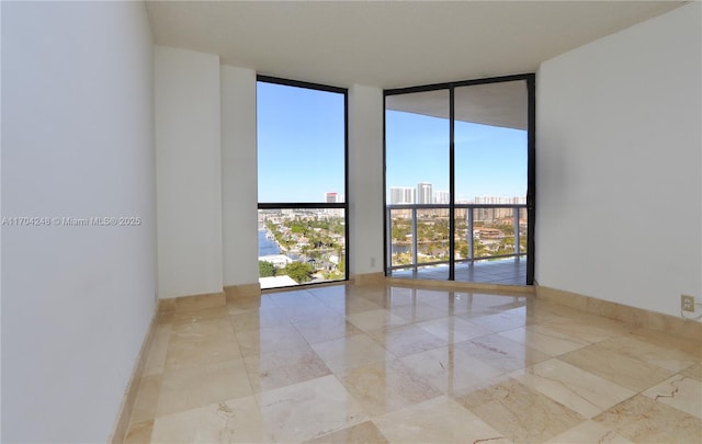 spare room featuring expansive windows, a view of city, and baseboards