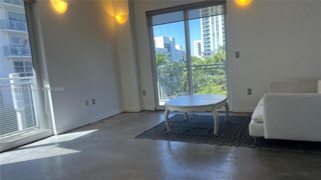 living room with concrete flooring, ceiling fan, and a healthy amount of sunlight