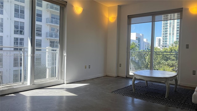 interior space featuring baseboards, a city view, and finished concrete floors