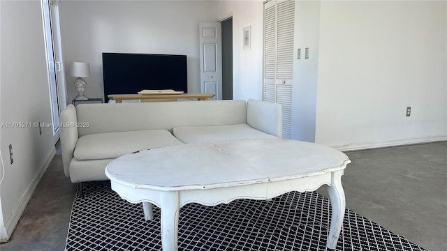 living area with baseboards and concrete flooring