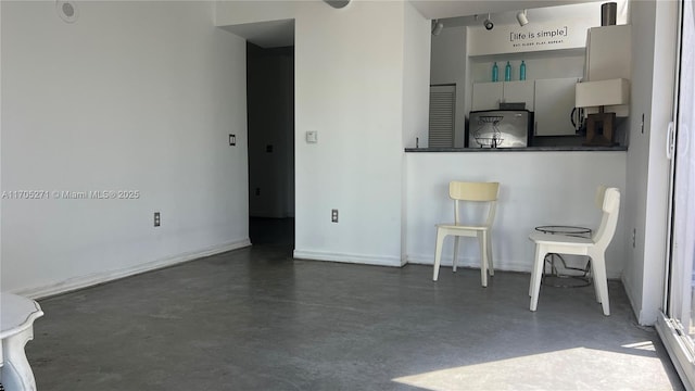 unfurnished living room with baseboards and finished concrete flooring