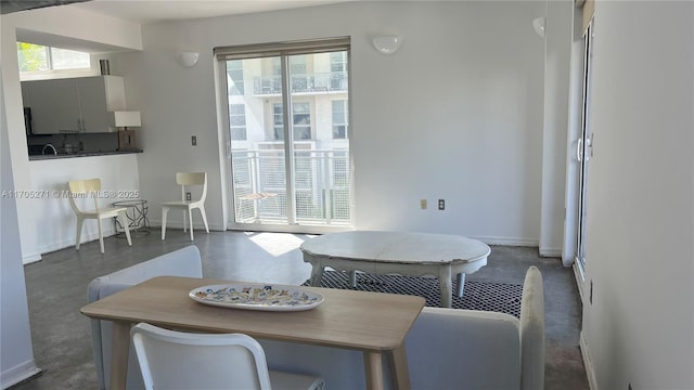 dining room featuring plenty of natural light, concrete floors, and baseboards