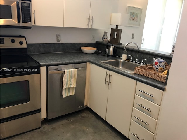 kitchen featuring dark countertops, white cabinets, appliances with stainless steel finishes, and a sink