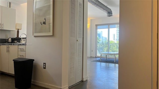 corridor featuring a sink, visible vents, baseboards, and finished concrete floors