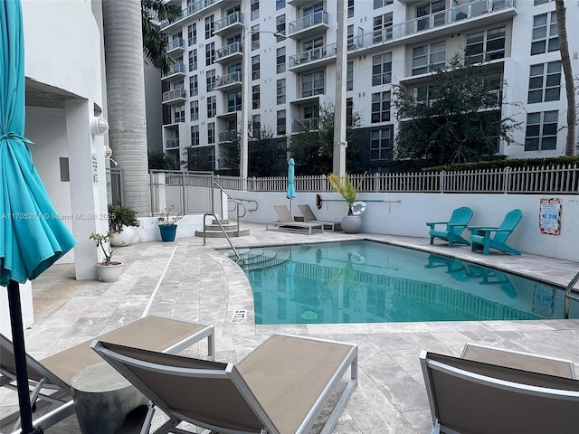 pool with a patio area and fence