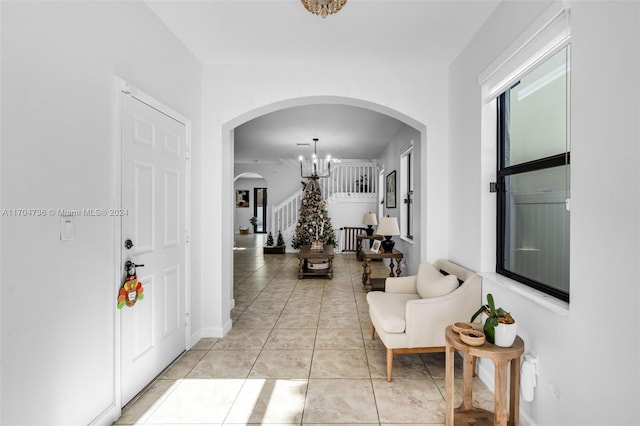 hall with light tile patterned floors and an inviting chandelier