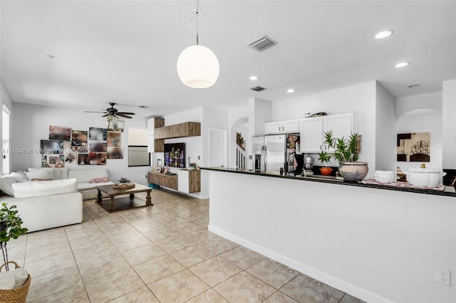 kitchen with pendant lighting, white cabinets, ceiling fan, stainless steel fridge, and a wealth of natural light