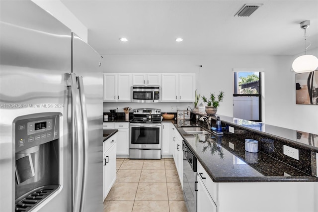 kitchen featuring white cabinets, sink, dark stone countertops, decorative light fixtures, and stainless steel appliances