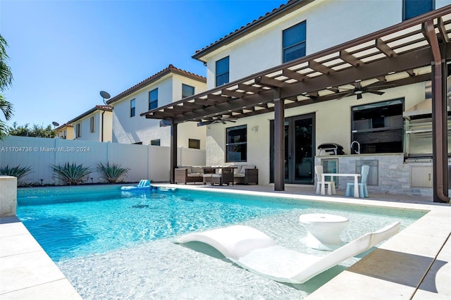 view of pool featuring an outdoor kitchen, ceiling fan, a pergola, and a patio