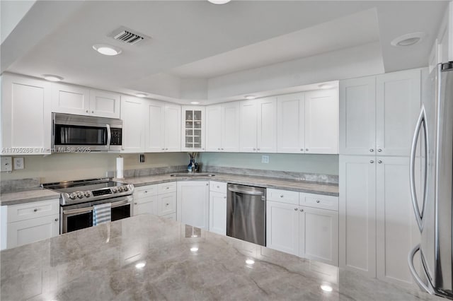 kitchen with white cabinetry, stainless steel appliances, light stone countertops, and sink