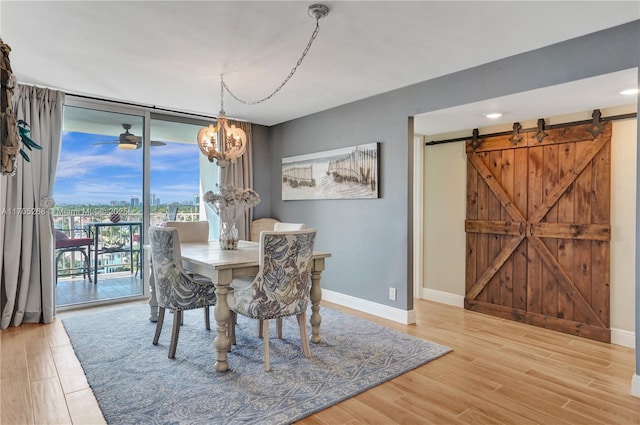 dining room with a wall of windows, a chandelier, wood-type flooring, and a barn door