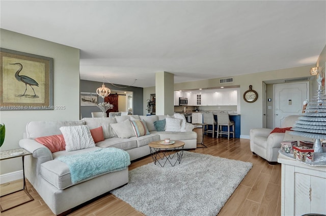 living room featuring a chandelier and light hardwood / wood-style floors