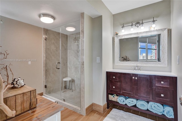 bathroom featuring hardwood / wood-style flooring, a shower with shower door, and vanity