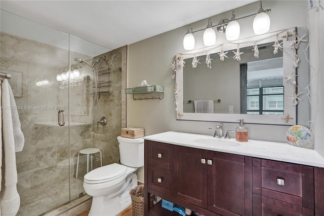 bathroom with toilet, a shower with shower door, and vanity