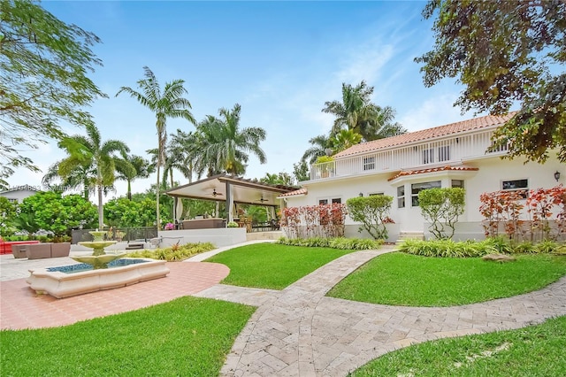 rear view of property featuring a patio area, stucco siding, a tile roof, and a yard