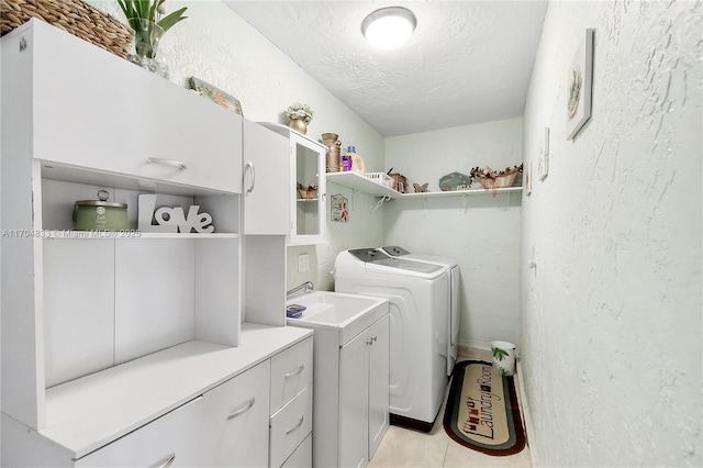 laundry room with cabinets, washing machine and dryer, light tile patterned floors, and a textured ceiling