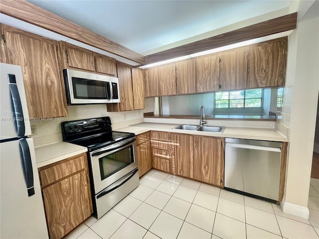 kitchen with light tile patterned flooring, appliances with stainless steel finishes, and sink