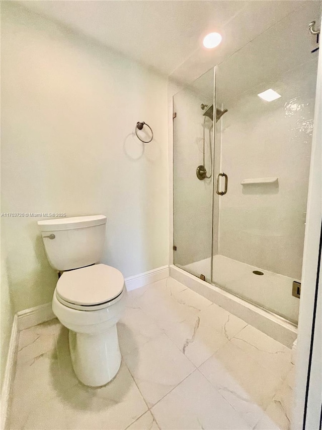 bathroom featuring a shower with shower door and toilet