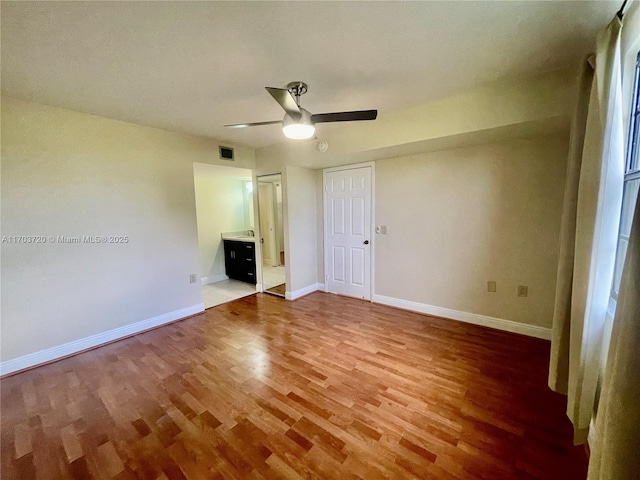 unfurnished bedroom with hardwood / wood-style floors, connected bathroom, and ceiling fan