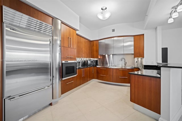 kitchen with decorative backsplash, sink, light tile patterned floors, and stainless steel appliances