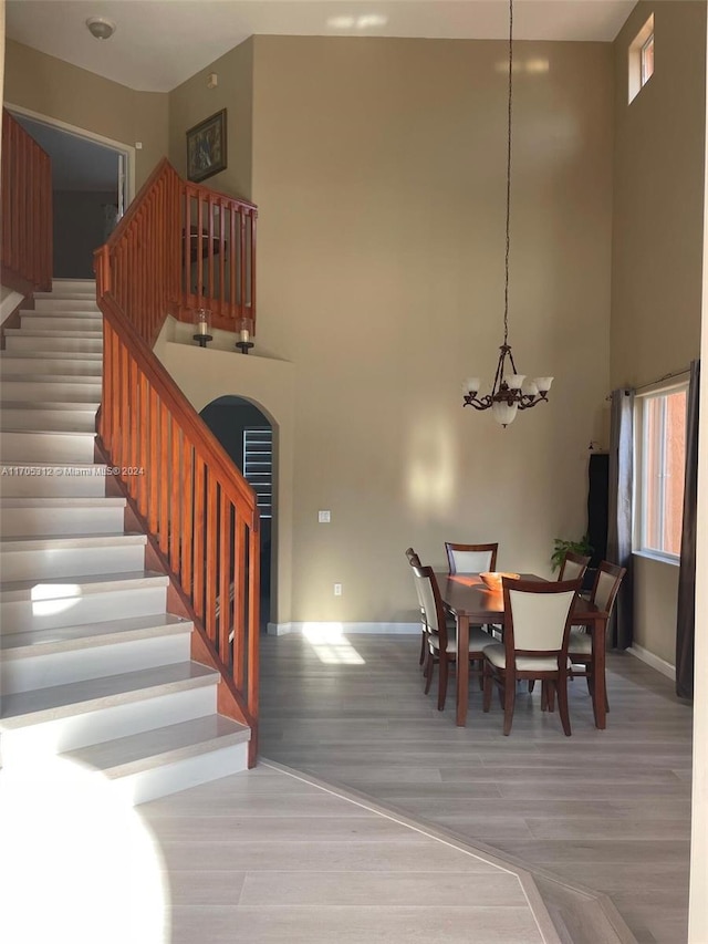 dining room featuring hardwood / wood-style floors, a towering ceiling, and an inviting chandelier