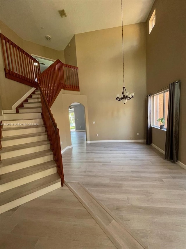 stairs with hardwood / wood-style flooring, a high ceiling, and an inviting chandelier