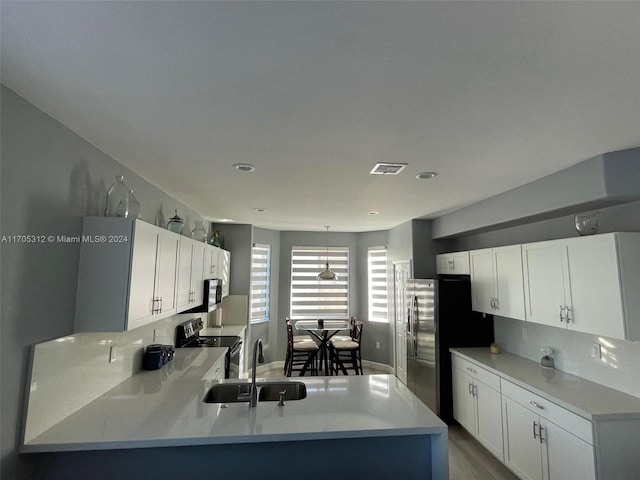 kitchen with sink, kitchen peninsula, light hardwood / wood-style floors, white cabinets, and appliances with stainless steel finishes