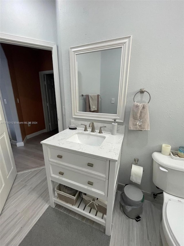 bathroom with vanity, hardwood / wood-style flooring, and toilet