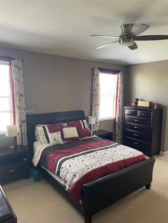 carpeted bedroom with ceiling fan and multiple windows