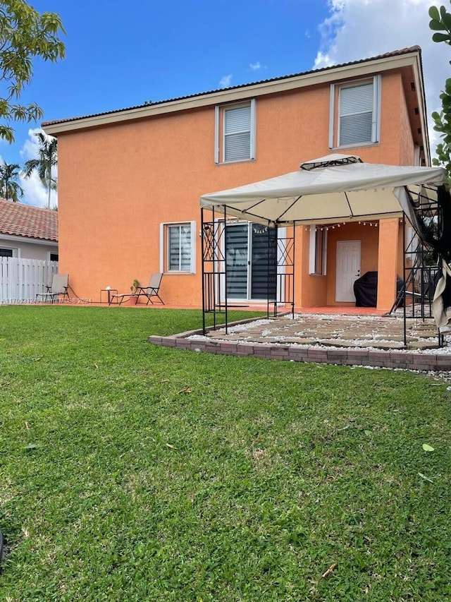 rear view of property featuring a gazebo, a patio area, and a yard