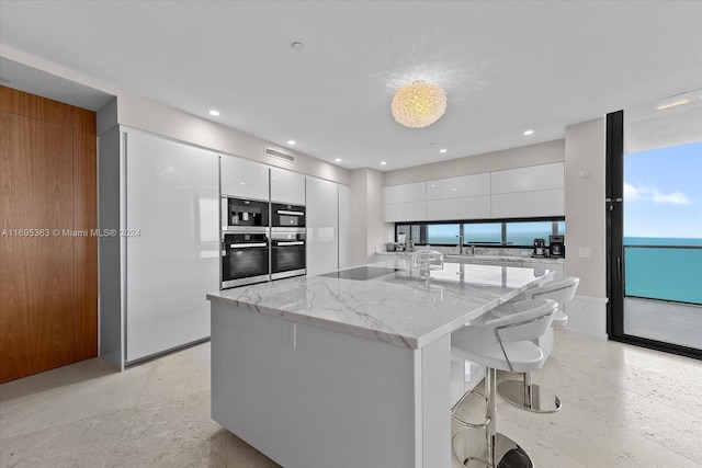 kitchen with a kitchen breakfast bar, white cabinetry, plenty of natural light, and light stone counters