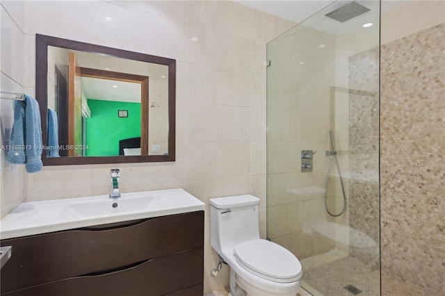 bathroom featuring a tile shower, vanity, toilet, and tile walls