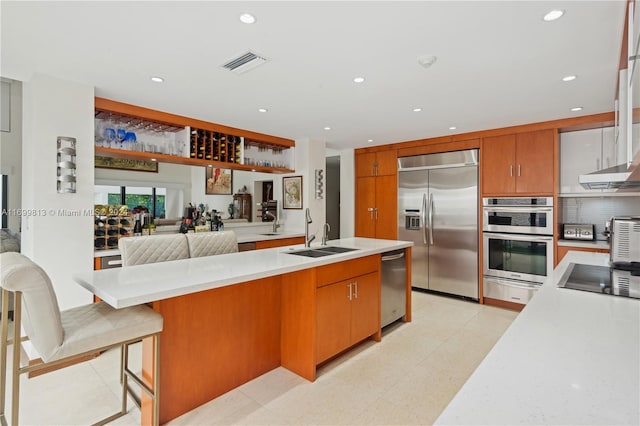 kitchen featuring backsplash, a breakfast bar, stainless steel appliances, sink, and a center island with sink