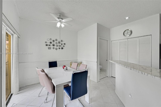 dining space featuring ceiling fan, light tile patterned flooring, and a textured ceiling