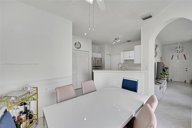 tiled dining area with ceiling fan and sink