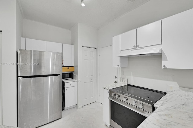 kitchen with appliances with stainless steel finishes, a textured ceiling, white cabinetry, and light tile patterned floors