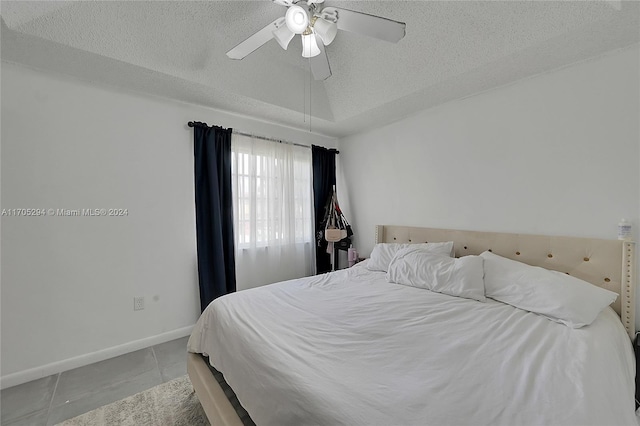 bedroom featuring ceiling fan, light tile patterned flooring, and a textured ceiling