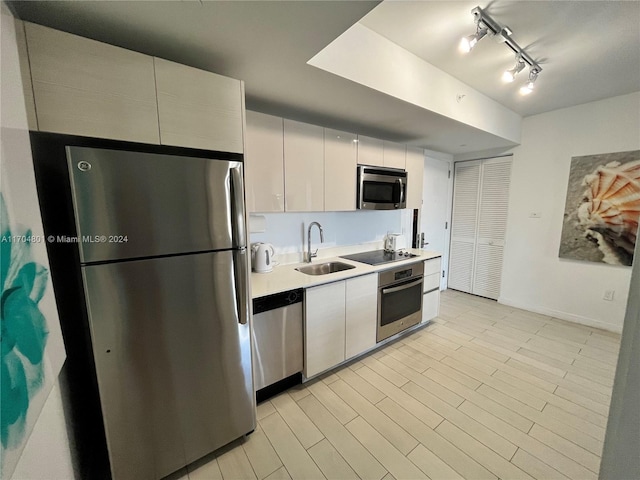 kitchen featuring white cabinets, sink, appliances with stainless steel finishes, and track lighting