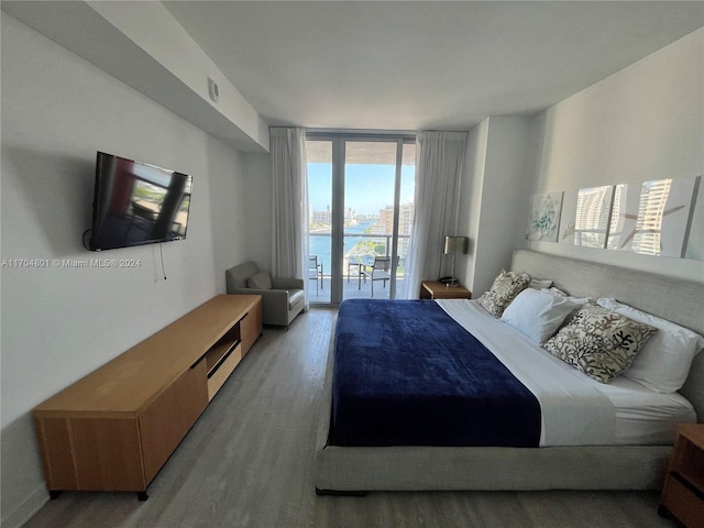 bedroom with access to outside, floor to ceiling windows, and wood-type flooring