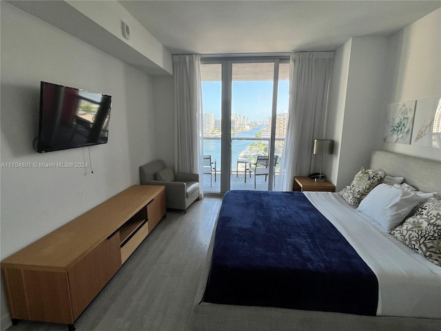 bedroom featuring access to exterior, a wall of windows, and light hardwood / wood-style flooring