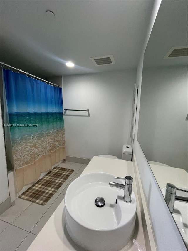 bathroom with tile patterned flooring, toilet, curtained shower, and sink