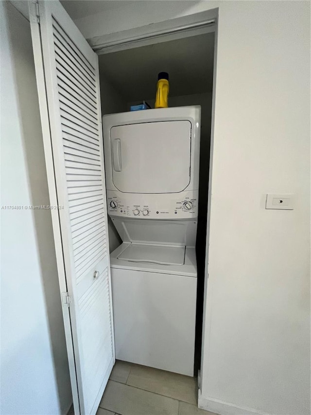 laundry room with stacked washer and dryer and light tile patterned floors