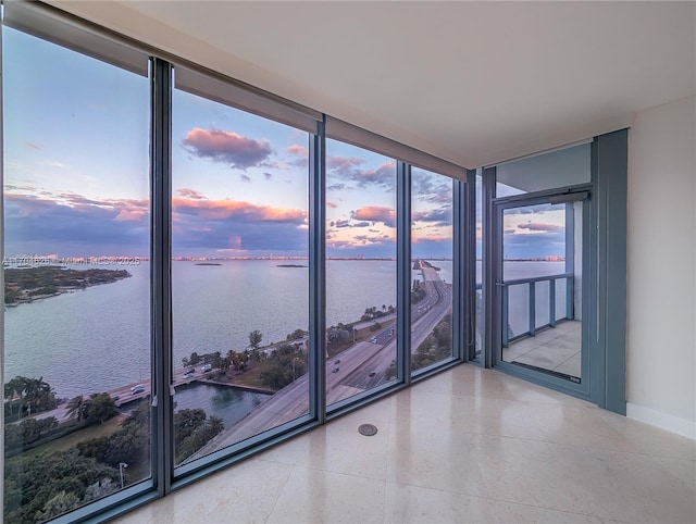 unfurnished room with expansive windows and a water view