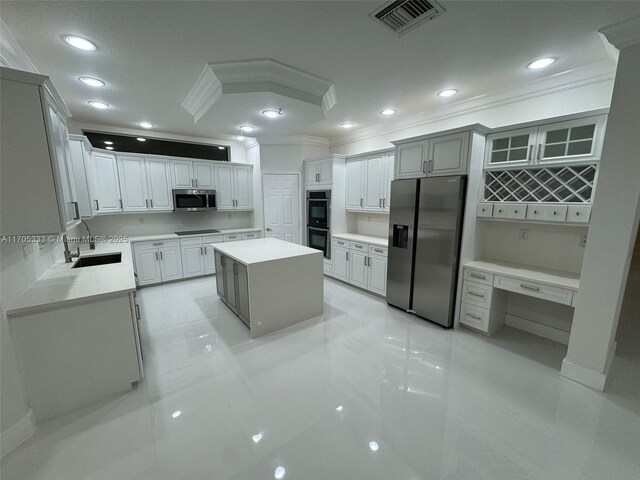 kitchen featuring sink, ornamental molding, light tile patterned floors, a kitchen island, and stainless steel appliances